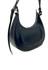 Černá kožená kabelka na rameno s zaobleným tvarem, zlatým zipem a uzlovými detaily na popruhu. Hladký povrch s jemným leskem.