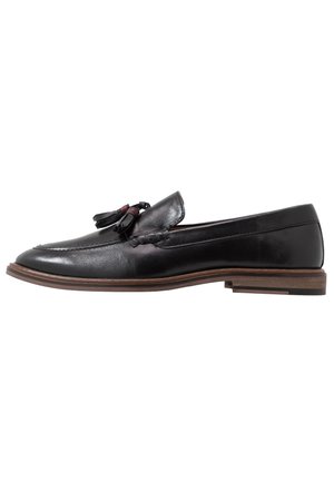 Czarne skórzane loafery o gładkim wykończeniu, z akcentami w postaci frędzli i lekko podwyższoną brązową podeszwą. Klasyczny design z haftowanymi detalami.