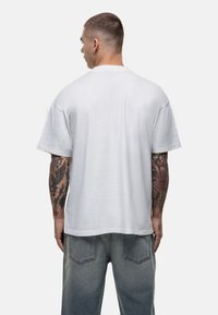 Witte katoenen t-shirt met een ontspannen pasvorm, korte mouwen en een ronde hals. Het heeft een zachte textuur en een minimaal ontwerp.