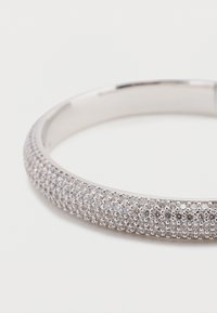 Ασημένιο βραχιόλι με λείο φινίρισμα, στολισμένο με μια σειρά από μικρομινιατούρες, λαμπερούς λίθους που δημιουργούν υφή κατά μήκος της επιφάνειας.