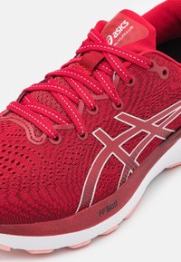Červená běžecká obuv Asics s bílým logem, červenými tkaničkami, prodyšným síťovaným svrškem a tlumením FF Blast v podrážce.