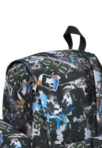 Černý batoh s kolážovým potiskem obsahujícím obrázky, palmové stromy a směs barev. Obsahuje zipové kapsy a látkovou smyčku na nošení.
