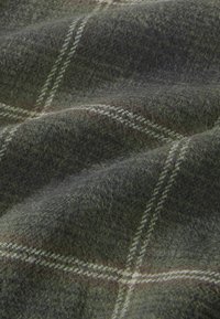 Tejido de lana en verde oscuro y gris con un patrón de cuadros. Presenta acentos en blanco y marrón, textura suave y un aspecto ligeramente difuso.