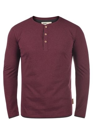 Bordeaux langemouwen henley shirt gemaakt van zachte stof, met een ronde halslijn en drie houten knopen aan de voorkant.