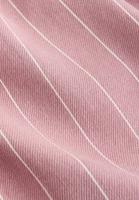 Tissu rose avec de fines rayures verticales blanches et un tissage texturé visible, présenté avec des plis doux et un éclairage tamisé.
