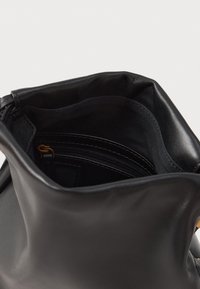 Melna ādas rokassoma ar mīkstu struktūru, ar rāvējslēdzēju slēdzamu iekšējo kabatu un auduma oderi. Atverot, atklājas gluda, matēta virsma.