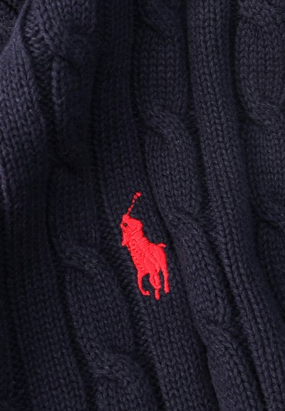 Tissu bleu marine en tricot torsadé avec un petit joueur de polo rouge brodé tenant un maillet.
