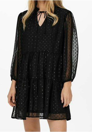 Schwarzes, gestuftes Kleid aus transparentem Stoff mit strukturierten Punkten, langen Puffärmeln und einer Schleife am Ausschnitt. Hat eine knieumspielende Passform.