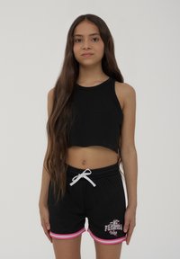 Top corto nero con scollatura rotonda, abbinato a pantaloni corti in rete neri con accenti rosa e un design grafico sulla gamba.