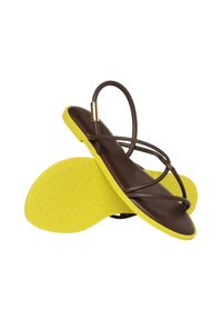 Sandales en cuir marron avec semelles en caoutchouc jaune. Elles présentent un design minimaliste avec de fines lanières croisées et une semelle extérieure texturée.