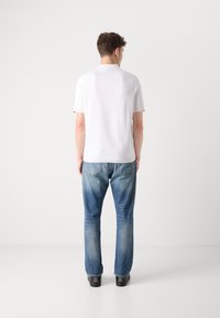 Hvit kortermet skjorte med kontrastkrage, paret med blå denim jeans. Antrekket har en avslappet passform og glatt tekstur.
