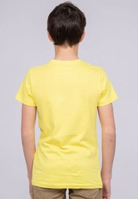 T-shirt en coton jaune avec un col ras du cou et des manches courtes, affichant une texture lisse et une coupe standard, vue de dos.