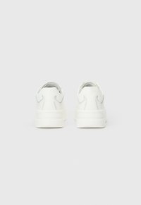 Sneakers bianchi con finitura in pelle liscia, cuciture sottili e tallone imbottito. Forma della punta arrotondata e design della suola in gomma piatta.