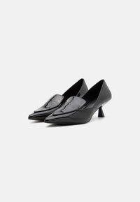 Black patent leather heels with a pointed toe, a low block heel, and a decorative upper panel. Smooth texture and sleek design.