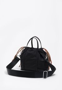 Bolsa de nylon negra con cordón y brillo sutil, doble asa superior y correa de hombro de tela removible. Presenta detalles decorativos de cuerda y herrajes metálicos.