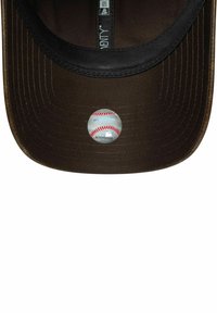 Cappello da baseball marrone con visiera nera, caratterizzato da una toppa circolare del logo MLB che raffigura una pallina da baseball sul lato interno della visiera.