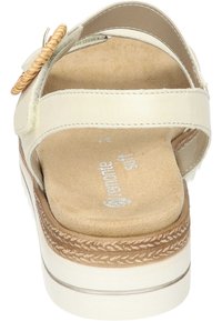 Witte leren sandaal met decoratieve geweven accents, tan gevoerde inlegzool en gevlochten details rond de zool. Plat ontworpen hak.