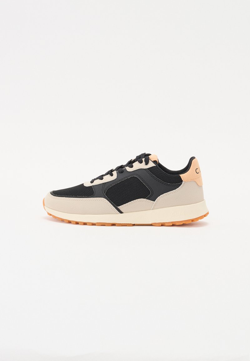 Schwarze und beigefarbene Sneaker aus Mesh- und Synthetikmaterialien, mit einer strukturierten Sohle, runden Schnürsenkeln und einem beigen Akzent an der Ferse.