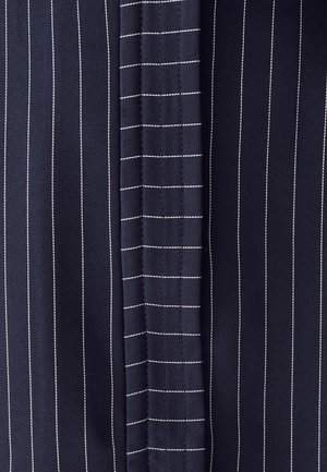 Marine stof met verticale streepjes en horizontale ruitjes. De textuur lijkt glad, met contrasterend witte stikdetails.