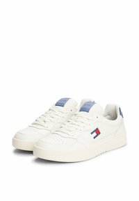 Zapatillas de cuero blancas con un diseño de corte bajo. Presentan acentos azules en la lengüeta y el talón, detalles perforados y un logo en el lateral.