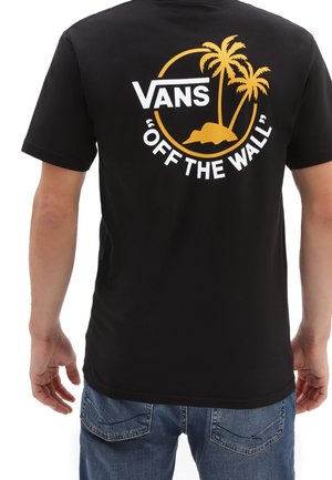 Schwarzes T-Shirt mit weißem Vans-Logo, gelben Palmen, Inselgrafik und dem Text "OFF THE WALL" auf der Rückseite, getragen mit blauen Jeans.