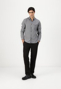 Gray button-up shirt with a checkered pattern, pocket detail, paired with black trousers and black boots. Simple, tailored design.