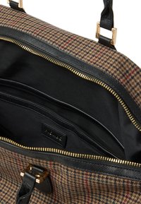 Texturiert braune und schwarze Tragetasche mit einem Hahnentrittmuster, goldener Reißverschluss und schwarzem Innenraum mit mehreren Fächern und einem Logopatch.