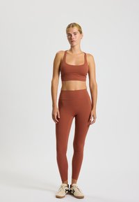 Braun Activewear-Set mit Sport-BH mit quadratischem Ausschnitt und hochgeschnittenen Leggings. Glatte Textur mit passgenauer Form und minimalen Nähten.