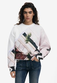 Sudadera blanca con un diseño gráfico colorido que incluye hojas de palma y patrones geométricos. Tela suave, corte relajado, puños acanalados.