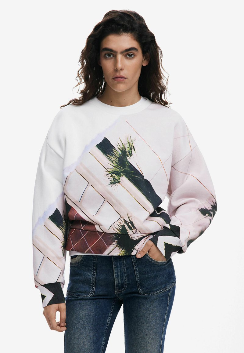 Sudadera blanca con un diseño gráfico colorido que incluye hojas de palma y patrones geométricos. Tela suave, corte relajado, puños acanalados.
