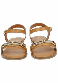 Braune Ledersandalen mit flachen Sohlen, verstellbaren Knöchellängen und einer dekorativen metallischen Kettenakzent auf dem Obermaterial. Die gesamte Oberfläche hat eine glatte Textur.