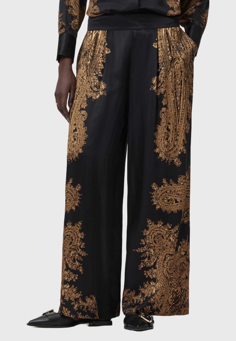 Mustad satiinpüksid kullavärvi paisley mustriga, laiad sääred, elastne vöökoht ja küljetaskud. Jalatsitel on musta rihma disain.