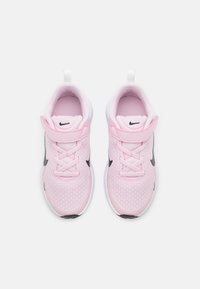 Zapatillas de color rosa claro con parte superior de malla, logo de Nike en negro, suela blanca y cierre de cordones rosa. Incluyen una pestaña en el talón para facilitar el uso.