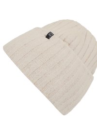 Knit beanie in light beige with a ribbed texture, featuring a small black logo tag. The design is fitted and slightly slouchy.