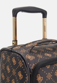 Zwarte koffer met gouden accenten, met een getextureerde buitenkant, een herhalend monogrampatroon en een uittrekbare handgreep.