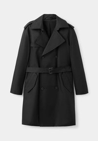 Trench-coat noir croisé avec de larges revers, taille cintrée par une ceinture, épaulettes et deux poches avant inclinées.
