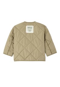 Veste matelassée marron clair avec couture en forme de losanges et une étiquette carrée blanche portant l'inscription « AMERICAN VINTAGE 2005 » sur le haut du dos.