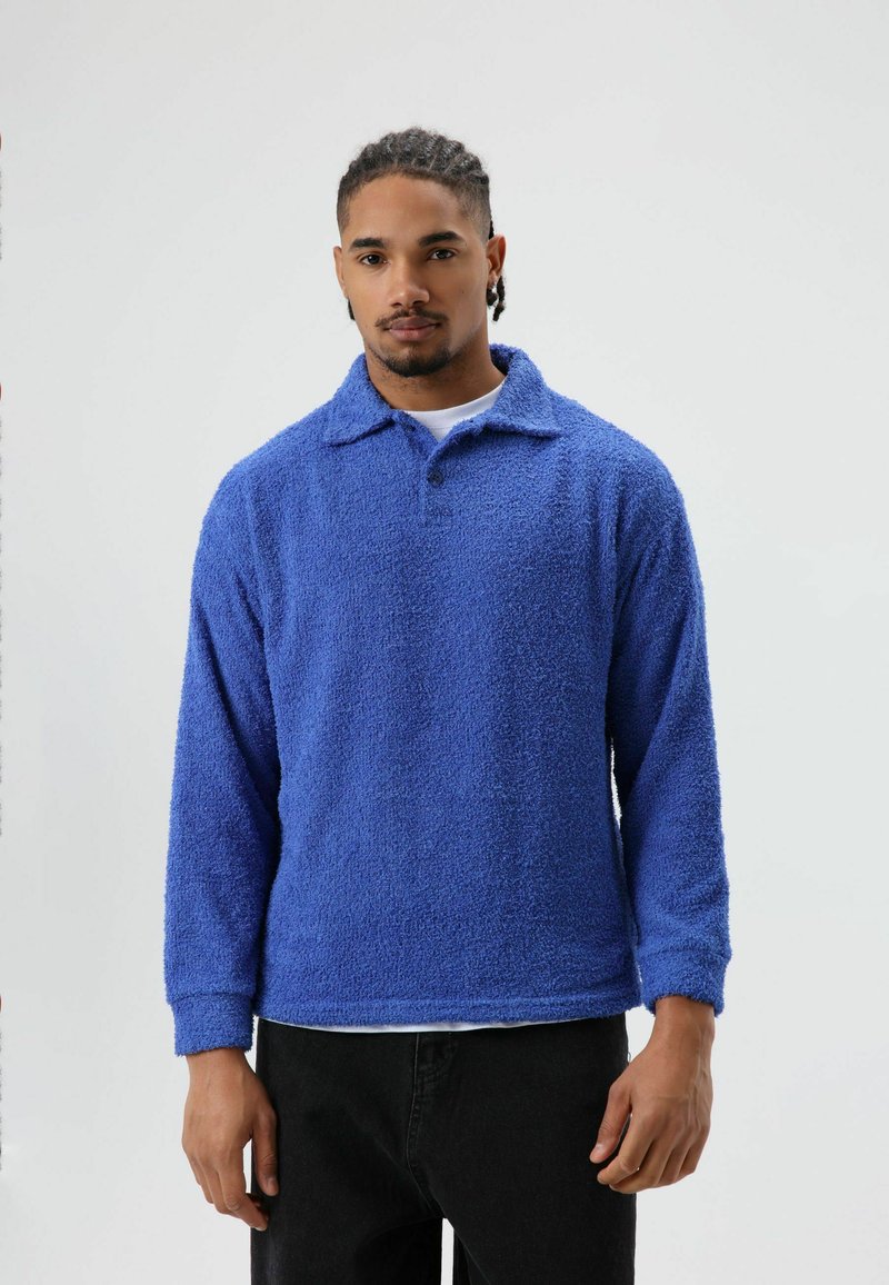 Blauwe fleece trui met een kraag, lange mouwen en een gestructureerde afwerking. Heeft een comfortabele pasvorm en een knopenbies bij de hals.