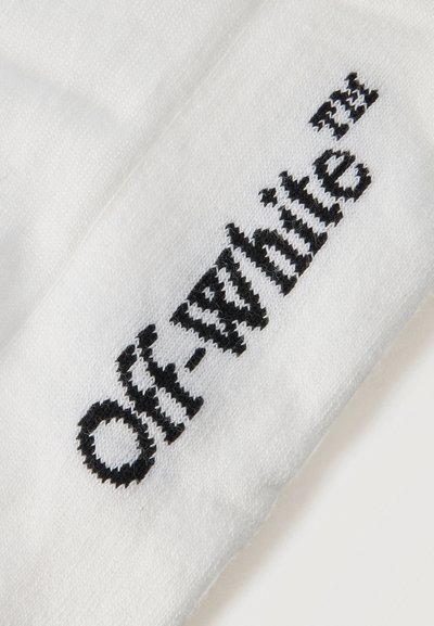 Λευκό ύφασμα με μαύρο πλεκτό κείμενο "Off-White™" σε κατακόρυφη διάταξη.
