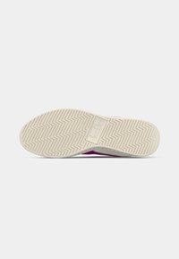 White rubber sole of purple sneaker with zigzag tread pattern and diadora logo embossed in center, shown from bottom view.