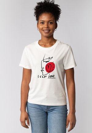 Witte katoenen t-shirt met een minimalistisch grafisch ontwerp van een gezicht met een rode hart en de tekst "SELF love" in het zwart. Korte mouwen.