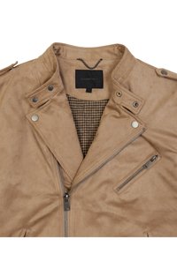 Jasny zamszowy kurtka z wyciętym kołnierzem, srebrnymi elementami, zamkiem błyskawicznym i zapięciem na zatrzaski, oraz podszewką w wzór houndstooth. Marka: Gianni Lupo.