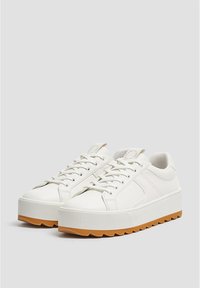 Baskets à plateforme blanches avec semelles en caoutchouc texturées, tige en cuir lisse, bout rond et design à six œillets avec lacets.