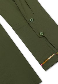 Olijfgroene shirt met twee groene knopen, een gladde textuur en een decoratieve geborduurde lijn in contrasterende kleuren langs de naad van de manchetten.