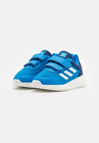 Niebieskie buty sportowe wykonane z oddychającej siateczki i materiałów syntetycznych, z białymi paskami, regulowanymi rzepami i białą podeszwą.