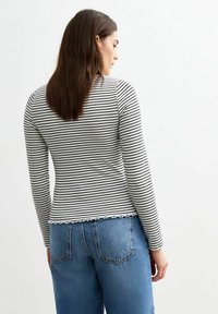 Langarm gestreepte top in zwart en wit, met een fitted silhouet en rafelige zoom. Gekocht met hooggezette blauwe denim jeans.