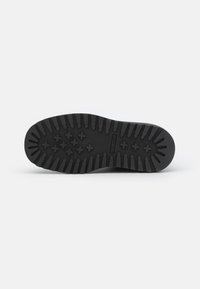 Sole di scarpe in gomma nera con modelli di battistrada profondi, caratterizzata da grip texturizzati e forme di stella prominenti per una migliore aderenza.