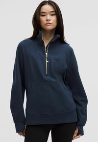 Navy blue pullover with a quarter zip, raglan sleeves, and kangaroo pocket. Features gold zipper accents and a soft, textured fabric.