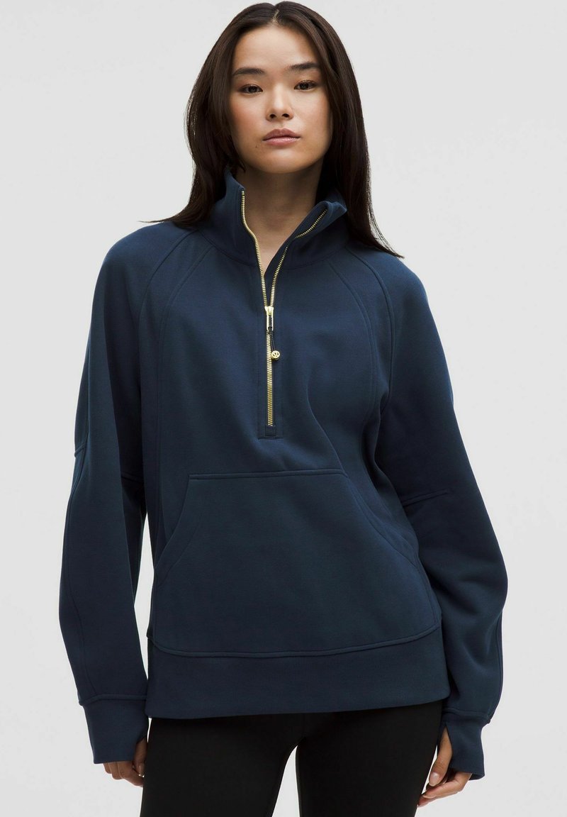 Navy blue pullover with a quarter zip, raglan sleeves, and kangaroo pocket. Features gold zipper accents and a soft, textured fabric.