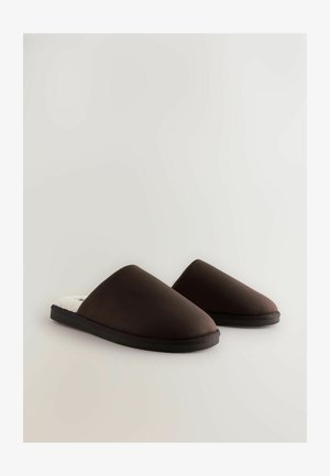 Brune slip-on tøfler med en glat stofoverflade, blød inderside og struktureret sort gummisål. Rund tådesign, minimalistisk stil.
